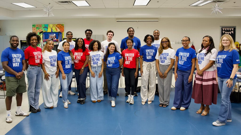 A group of young professionals pose in a classroom