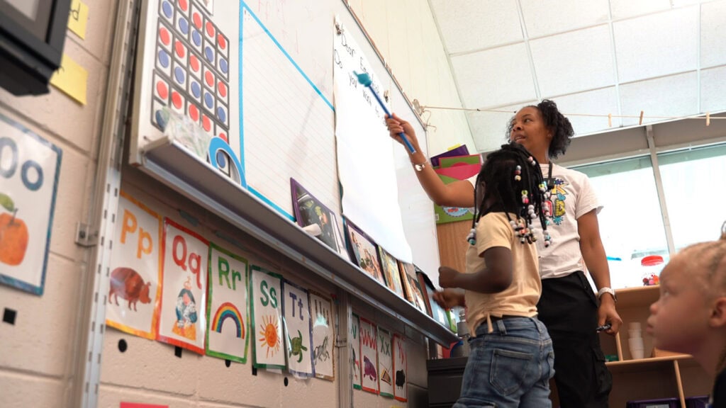 A teacher points to words for students to read aloud in a kindergarten classroom
