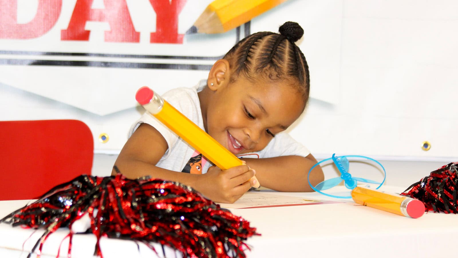 Atlanta student participating in Kindergarten Signing Day, signing with an oversized pencil