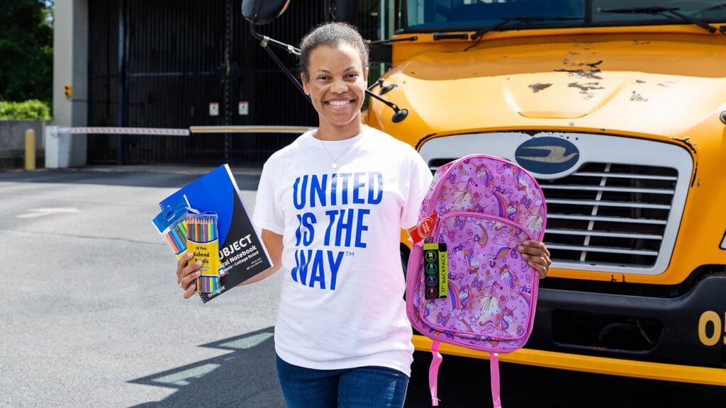 Volunteer holds up school supplies at one of United Way of Greater